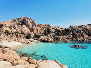Una costa rocosa con aguas turquesas cristalinas y una playa de arena.