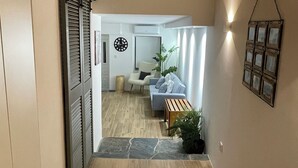 Un passadís amb sòl de fusta, una porta corredissa, un sofà, una taula petita i una decoració penjada a la paret.