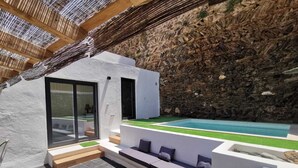 Una zona exterior moderna amb piscina, mur de pedra i seients integrats.