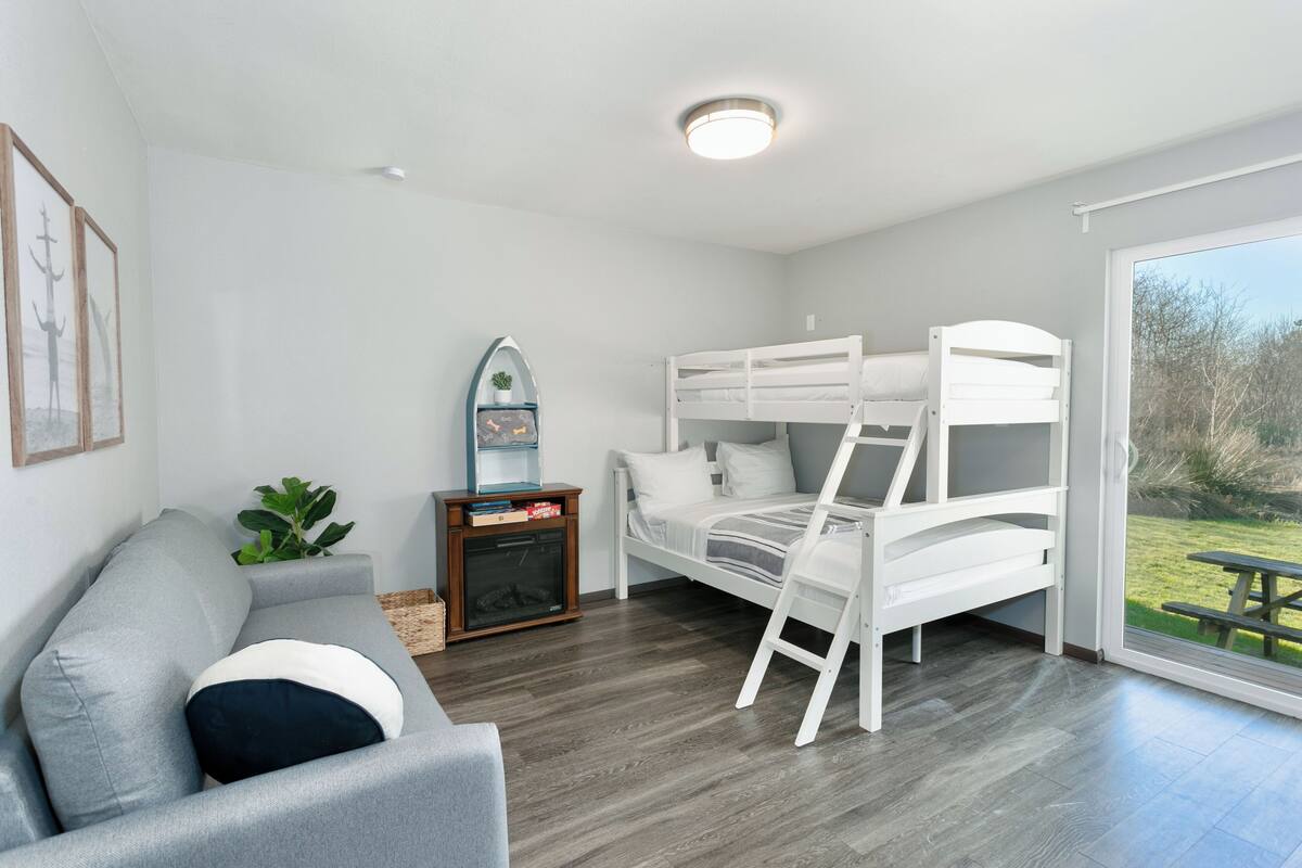 A modern room with a bunk bed, a sofa, a small table, and a plant.
