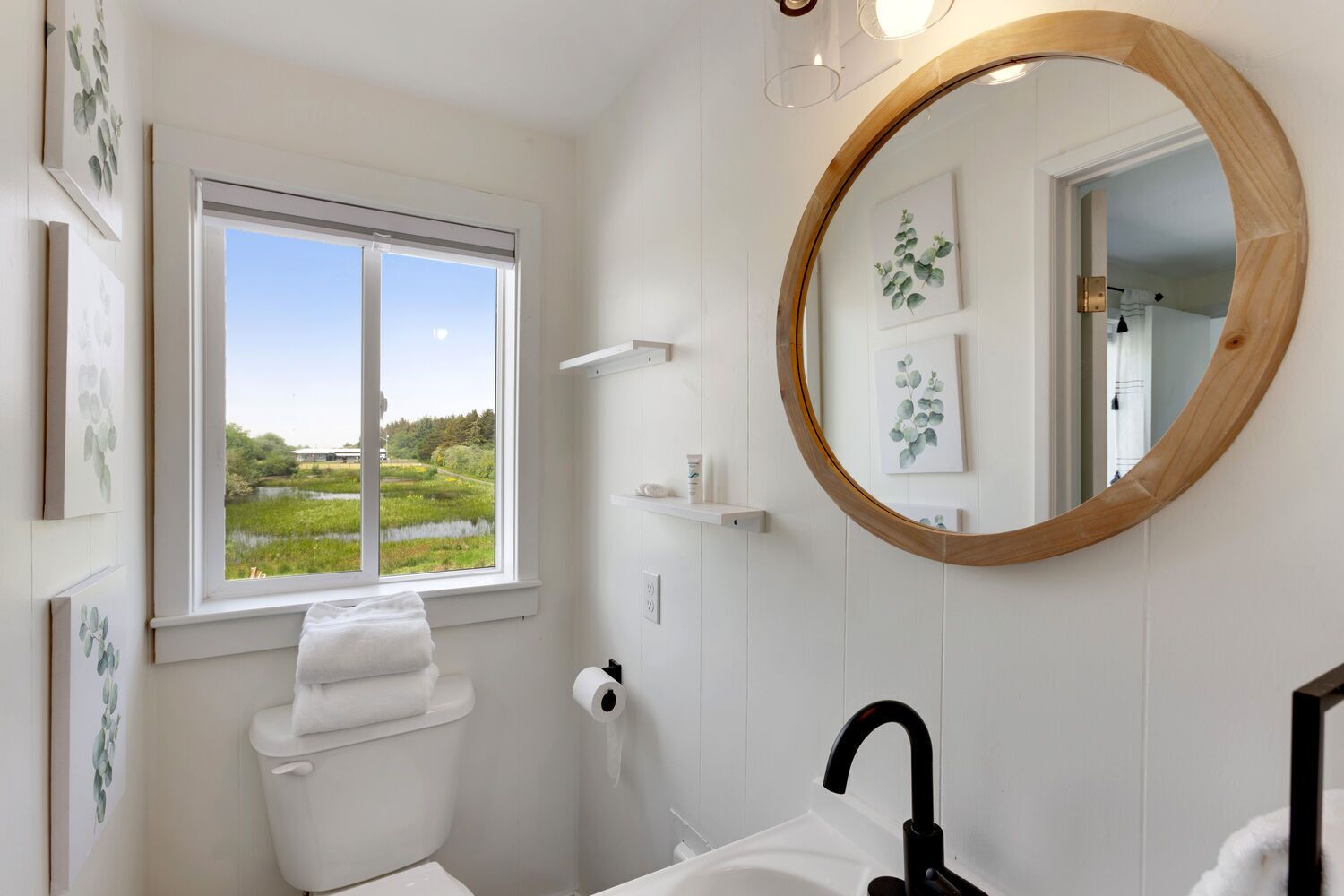 A bathroom with a toilet, sink, and a large mirror.