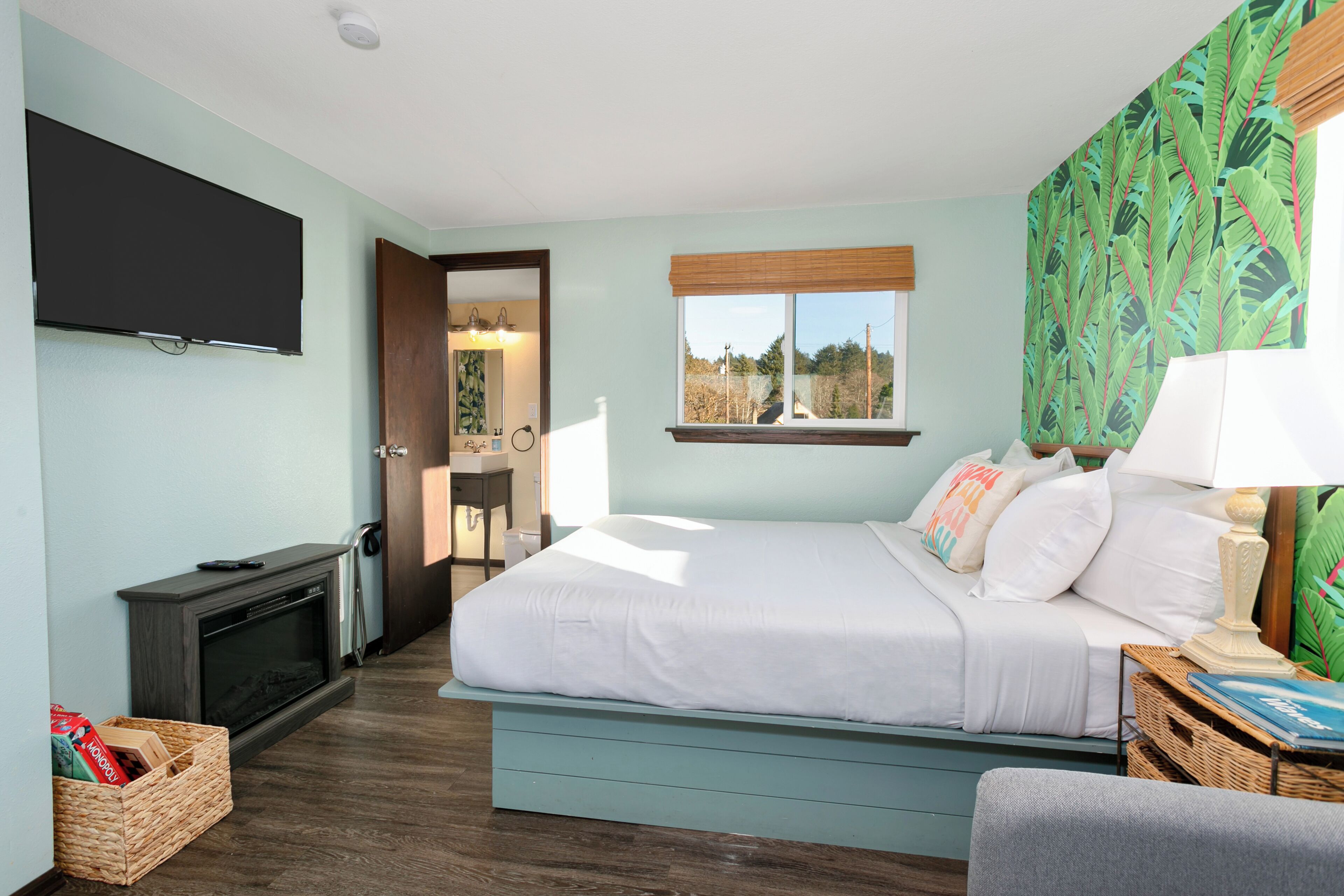 A bedroom with a bed, a television, a window with a view, and a fireplace.