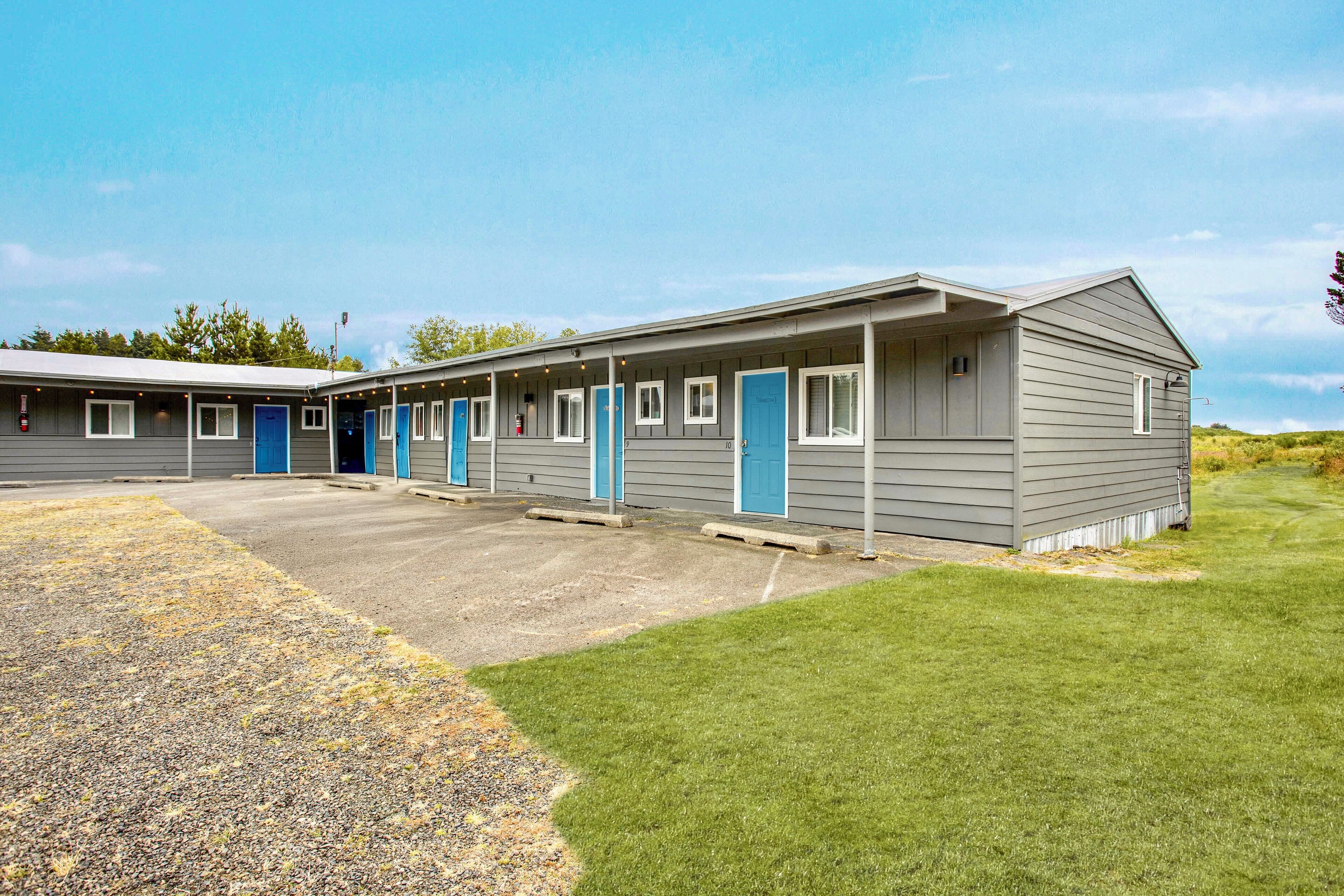 A motel with a row of rooms featuring blue doors and a covered parking area.