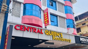 Ein Gebäude mit einem Schild, das "Central Queen's Residency" und "Menin Men's Wedding Collection" zeigt.