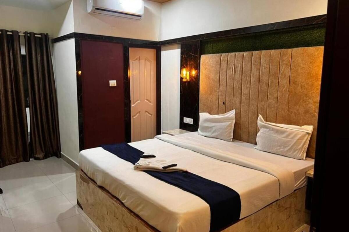 Una habitación de hotel con una cama grande, un cabecero de madera y una puerta roja.