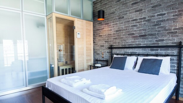 Un dormitorio moderno con una cama grande, un armario de madera y una pared de ladrillo.