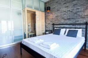 A modern bedroom with a large bed, a wooden wardrobe, and a brick wall. - Stylish Sauna Retreat Apt in Gazi (Athens)