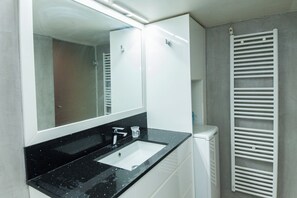 A bathroom with a black countertop sink, a mirror, and a white radiator. - Stylish Sauna Retreat Apt in Gazi (Athens)