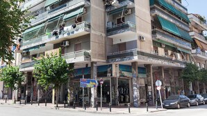 Un edificio de varios pisos con balcones, una fachada comercial y vista a la calle.