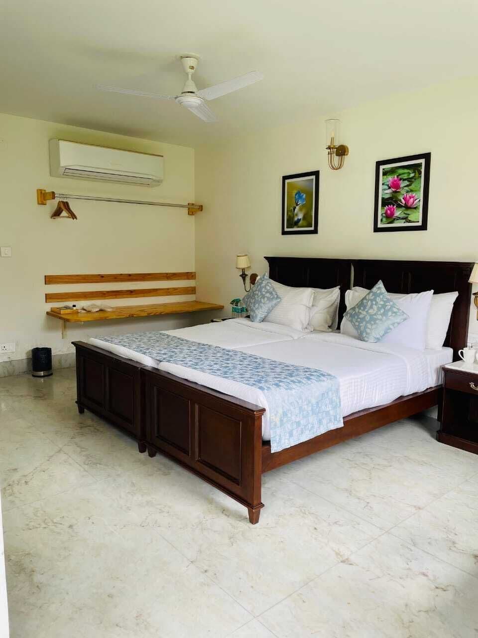 A bedroom with a wooden bed, a ceiling fan, an air conditioner, and two framed pictures on the wall.