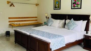 A bedroom with a wooden bed, a ceiling fan, an air conditioner, and two framed pictures on the wall.
