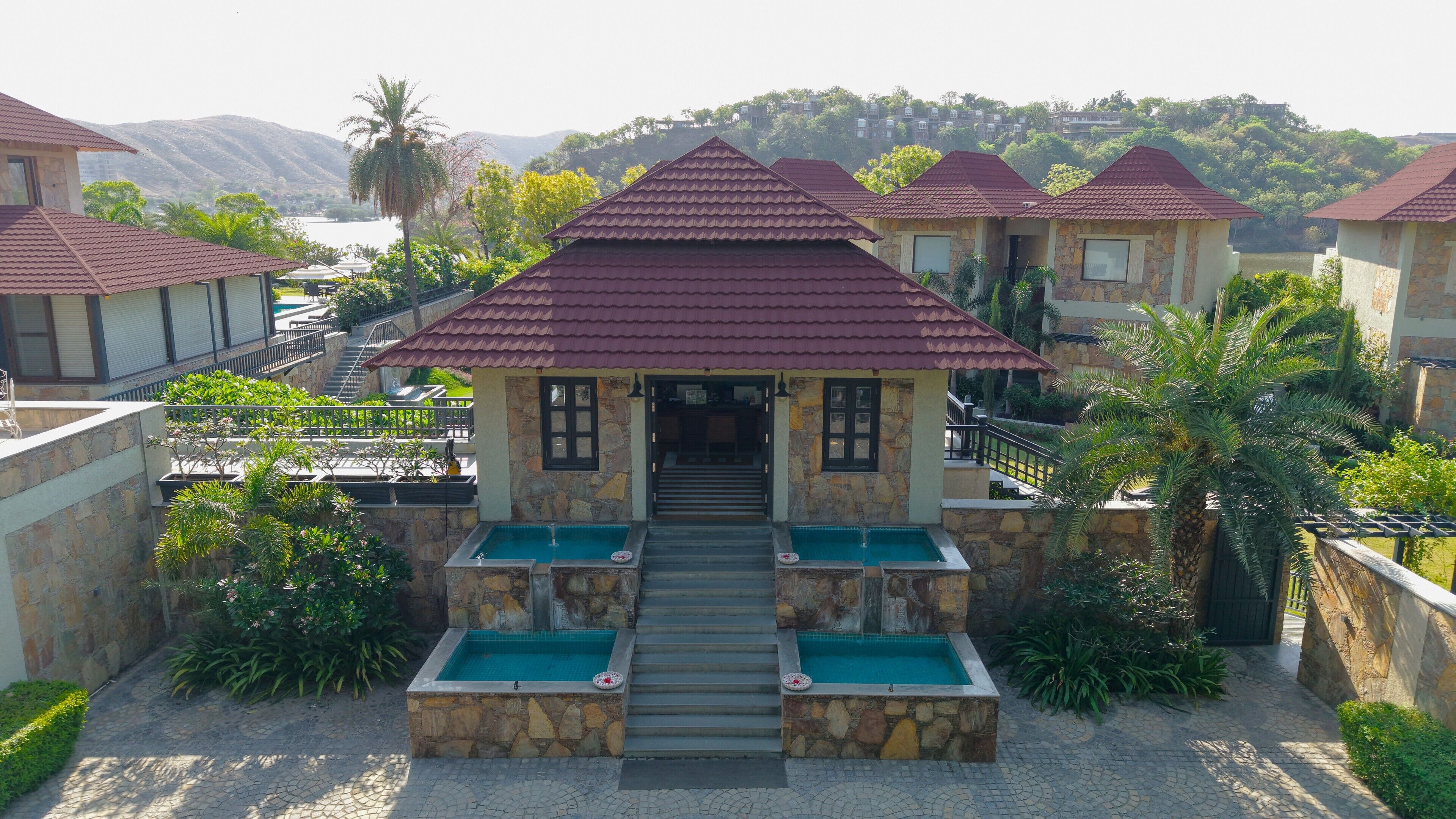 A building with a stone facade, a red-tiled roof, and a pool area with steps leading to the entrance.