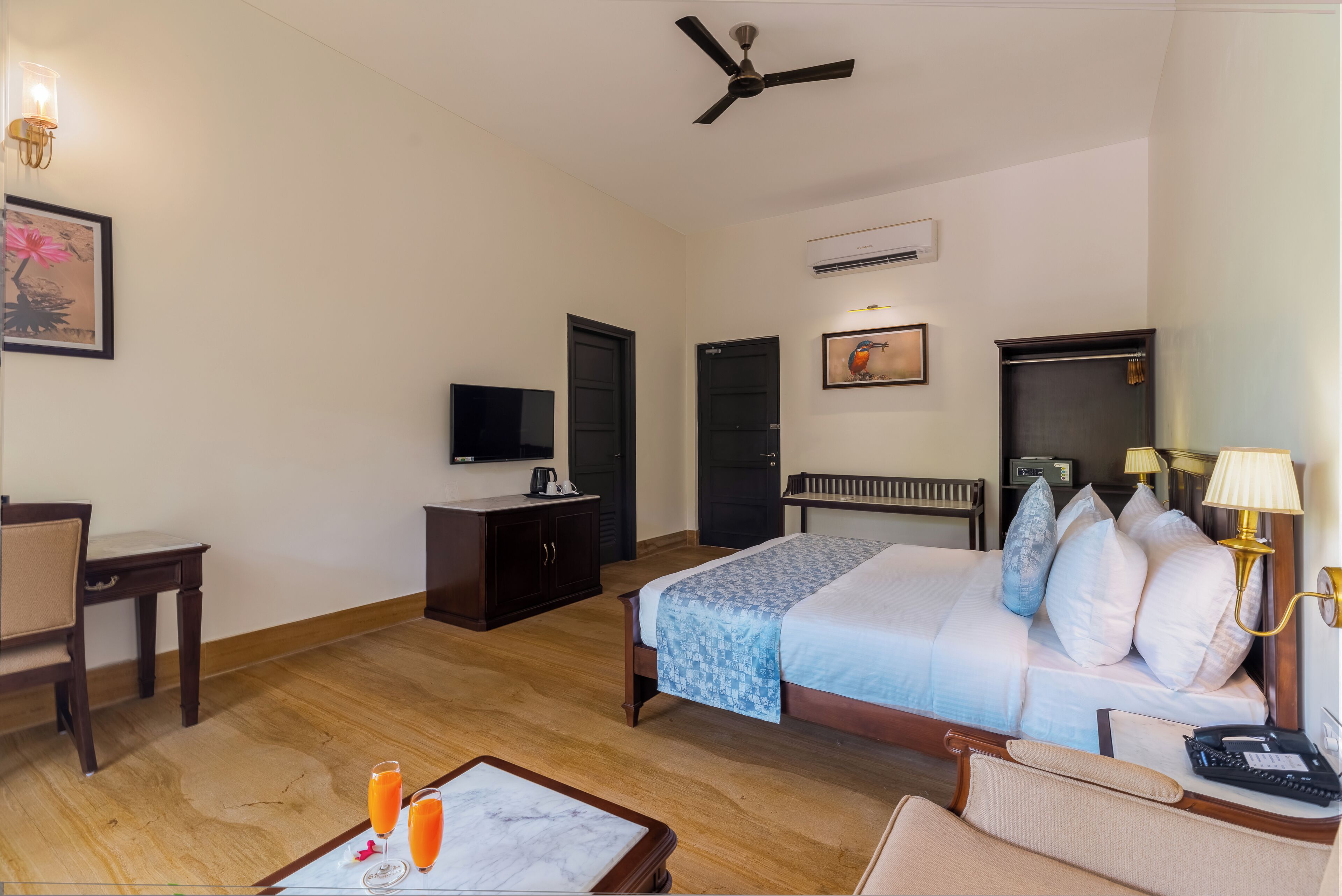 Una camera d'albergo con un letto, una scrivania, una sedia, un televisore e una ventola a soffitto.