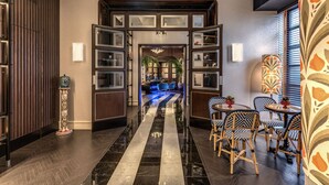Un vestíbulo de hotel con piso a rayas blanco y negro, paneles de madera y un mostrador de recepción con sillas.