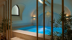 Un área de spa con un jacuzzi, decoración de bambú y una zona de estar con una silla acolchada.