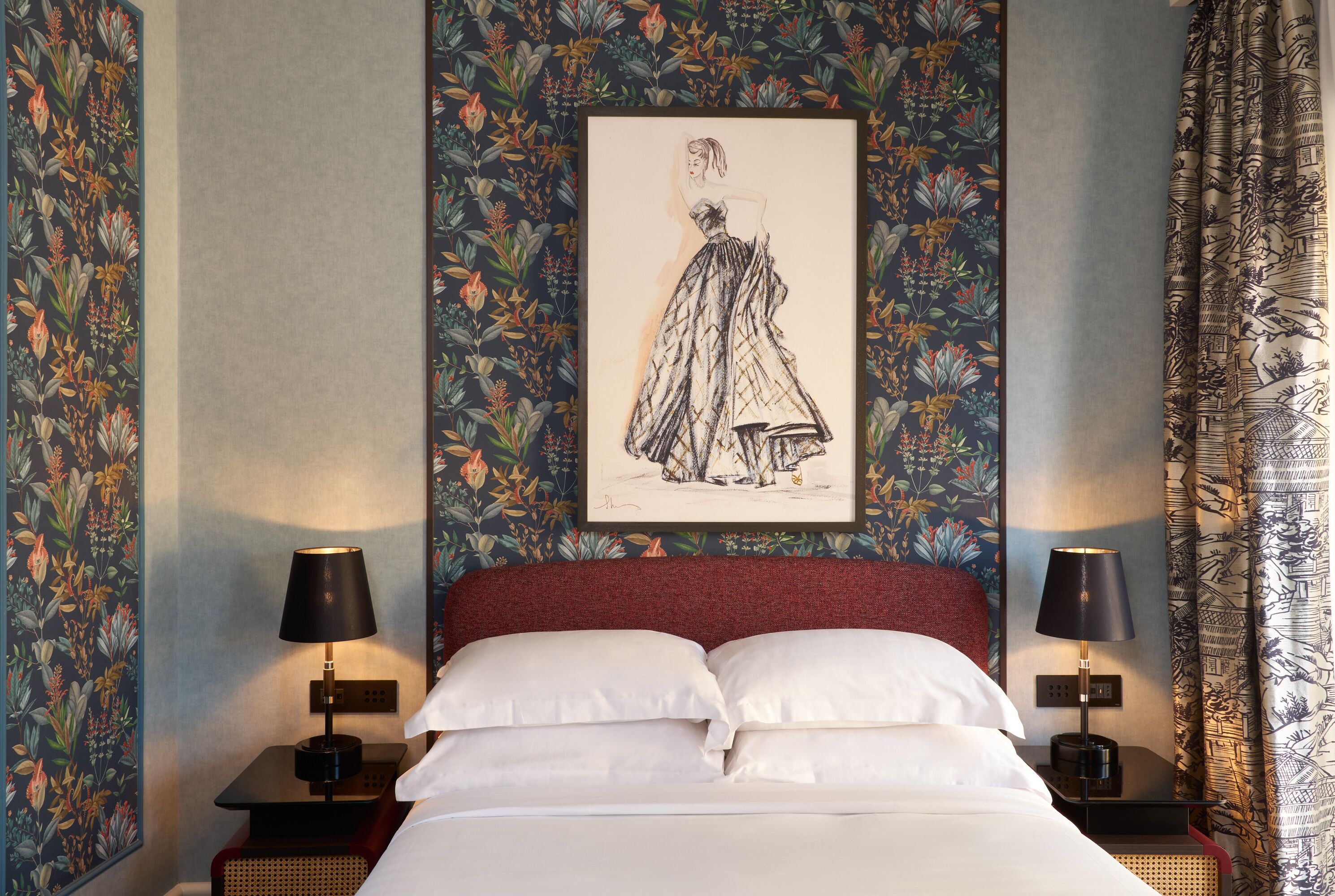 Een net opgemaakt bed met witte lakens, twee nachtkastjes met lampen, en een lijst met een illustratie aan de muur.