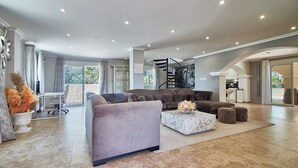 Ein geräumiges Wohnzimmer mit grauem Sofa, einem weißen Couchtisch und einer modernen Treppe.