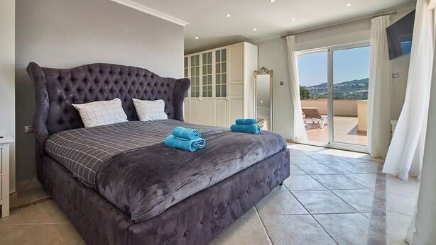 Ein großes Bett mit einem gesteppten Kopfteil, ein Kleiderschrank und ein Balkon mit Blick.