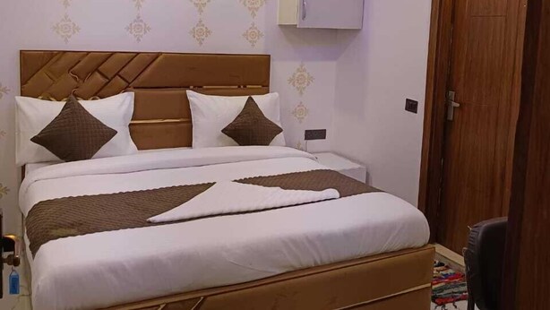 A bedroom with a bed, a ceiling fan, and a wardrobe. - Roomshala 061 NK Residency (New Delhi)