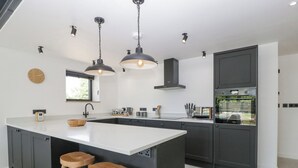 Une cuisine moderne dotée d’un grand îlot central, de meubles de couleur sombre et d’un éclairage suspendu.