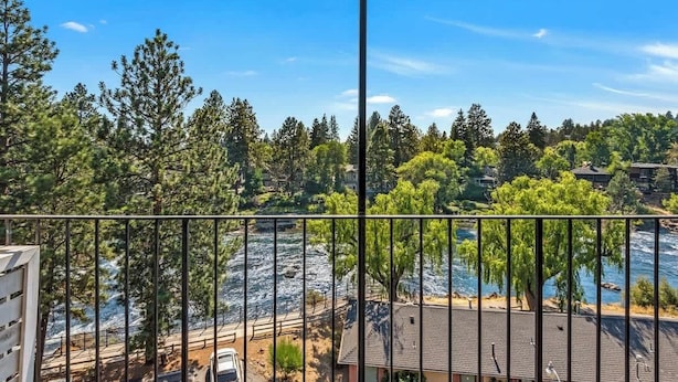 Un balcone con vista su un fiume, alberi e un edificio sullo sfondo.