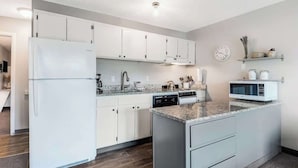 Una cucina moderna con mobili bianchi, forno integrato, microonde e un piano di lavoro in granito.