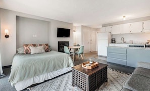 A compact hotel room with a bed, a small dining table, a TV, a kitchenette, and a sofa. - Riverview Pet Friendly Condo in Downtown Bend (Bend)