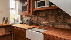 Una cocina con armarios de madera, un lavamanos blanco, un microondas y un tostador.