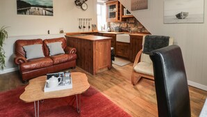 Una sala de estar acogedora con un sofá de cuero, un tapete rojo y una mesa de centro de madera.