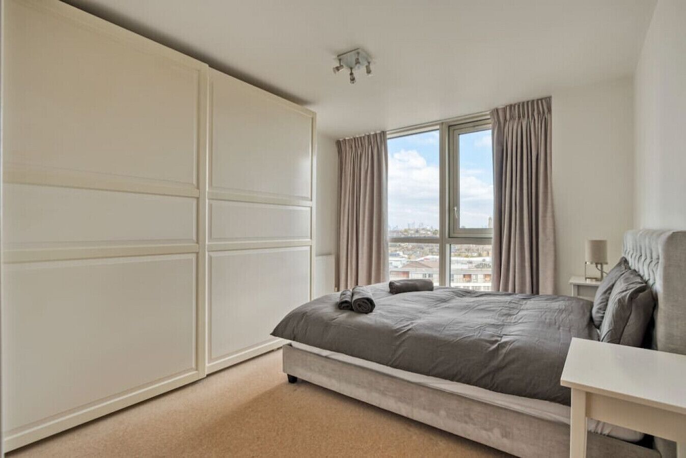 Ein Schlafzimmer mit Bett, Schreibtisch, Kleiderschrank und einem Fenster mit Vorhängen.