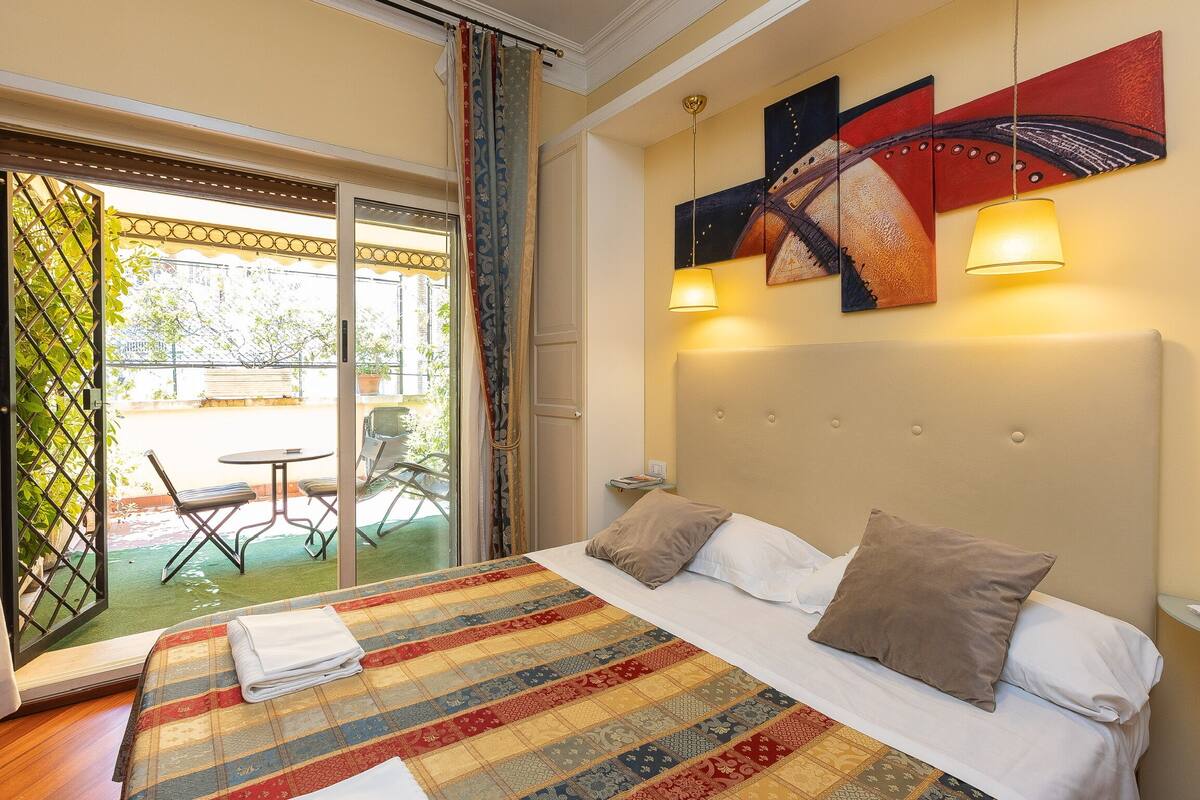 Quarto de hotel com uma cama, vista para a área externa e obras de arte na parede.