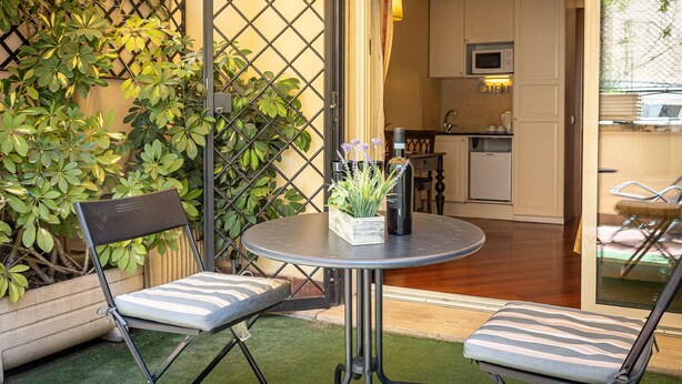 Eine kleine Terrasse mit zwei Stühlen, einem Tisch und einem Blumentopf.