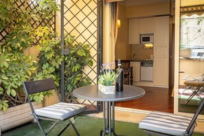 A small patio with two chairs, a table, and a potted plant.