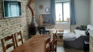 Un salon chaleureux avec un mur en pierre, une table à manger en bois et un canapé confortable.
