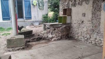 Un espacio al aire libre rústico con pared de piedra, suelo de concreto y una estructura de madera con cajas verdes y marrones.