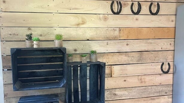 Un mur avec des lattes de bois et trois caisses noires disposées verticalement.