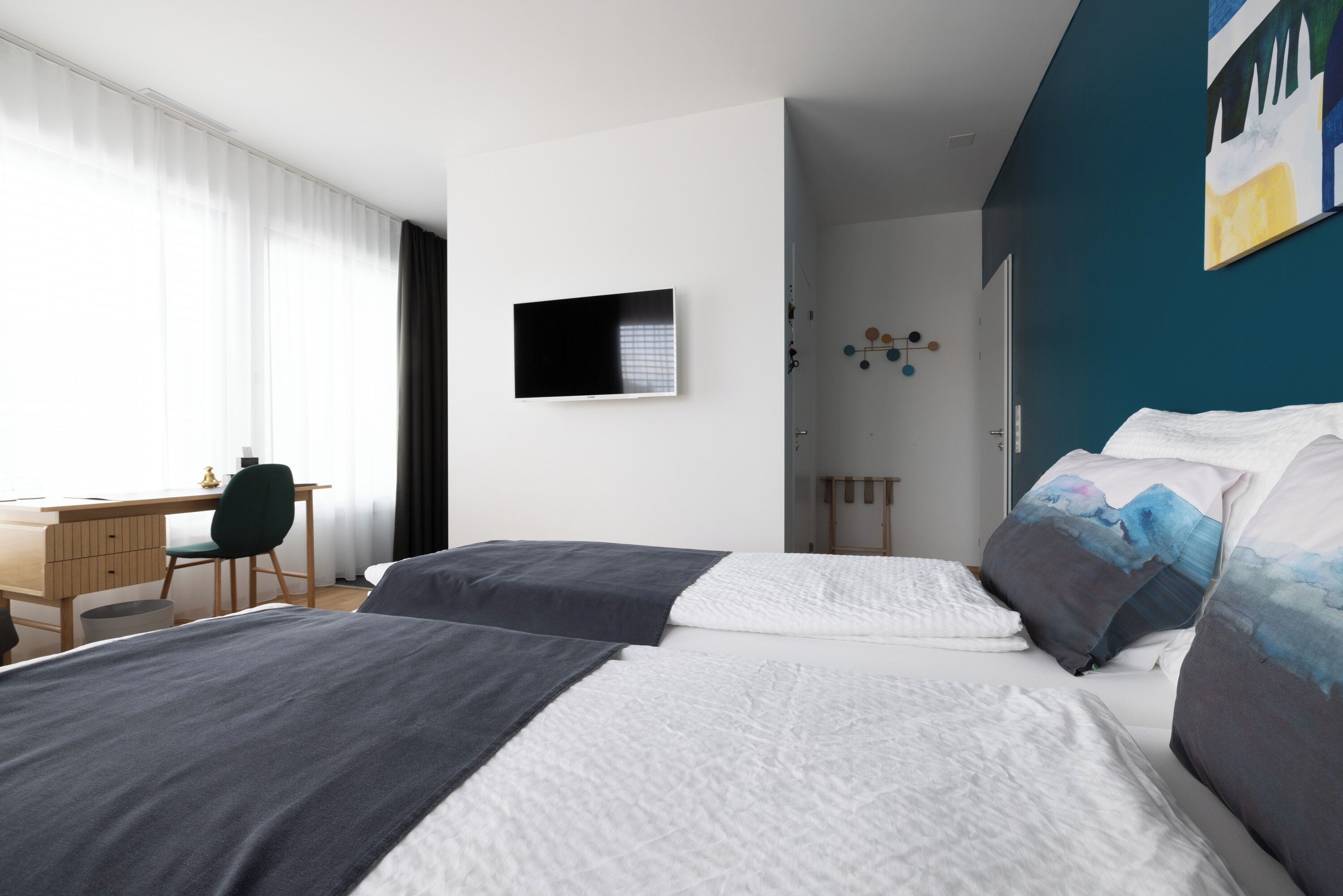 Een moderne hotelkamer met twee bedden, een bureau en een televisie.