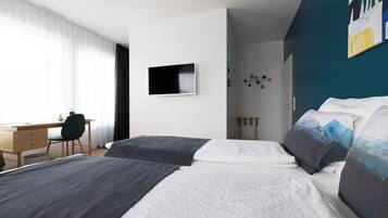 Een moderne hotelkamer met twee bedden, een bureau en een televisie.