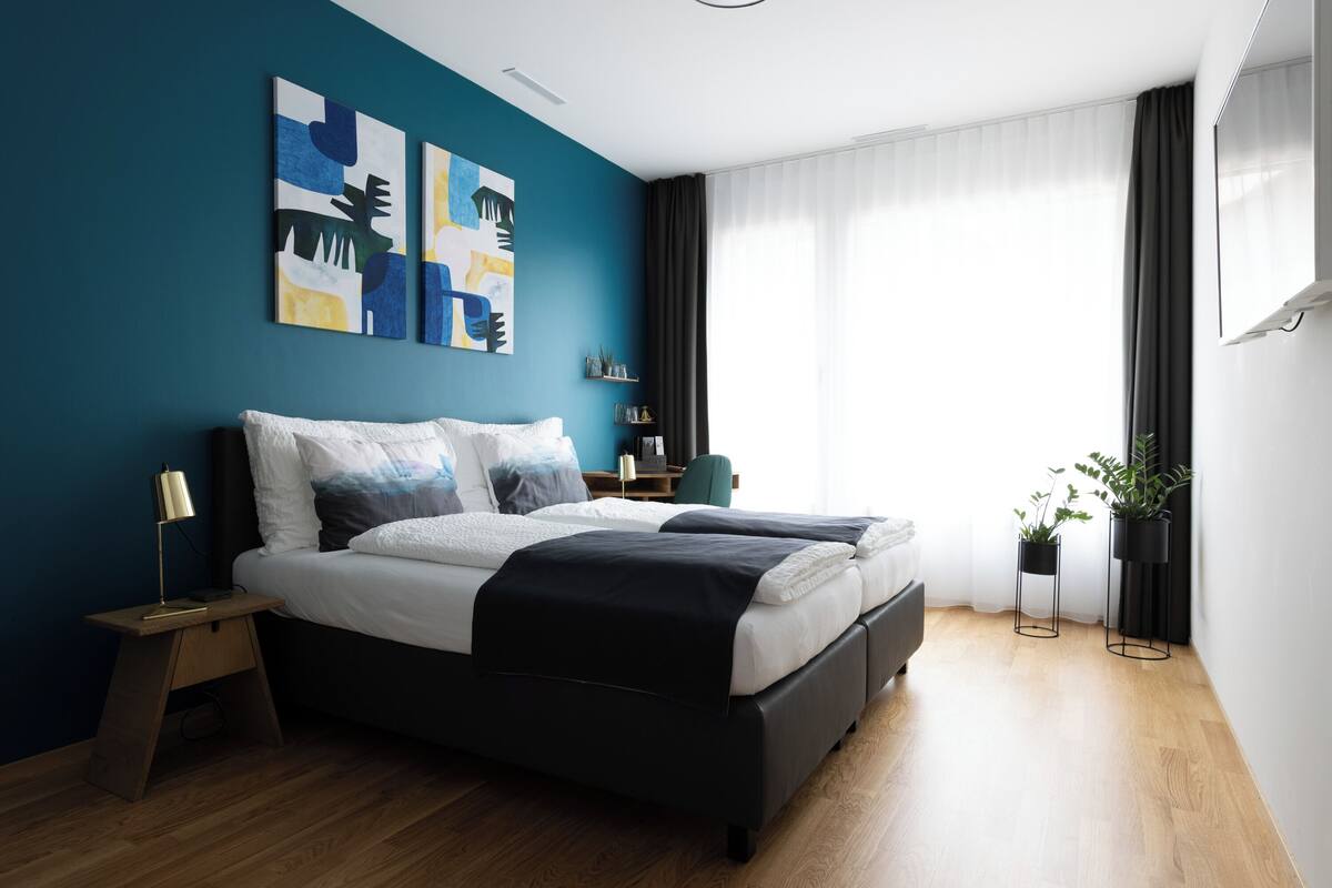 A modern bedroom with a bed, bedside tables, and artwork on the wall.