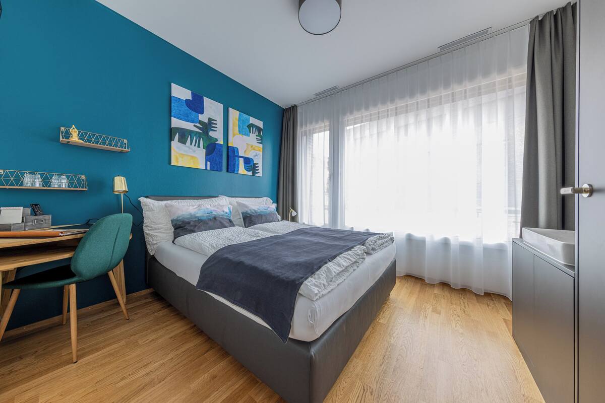 A modern bedroom with a bed, a desk, and a chair.