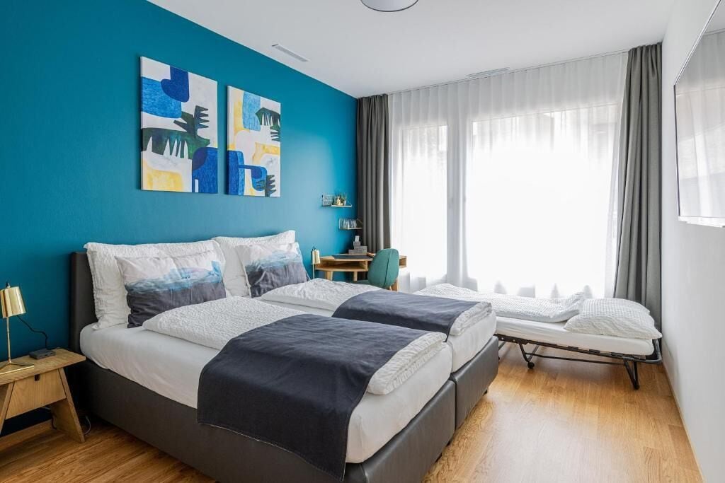 Una habitación de hotel moderna con dos camas, un escritorio y una ventana con cortinas.