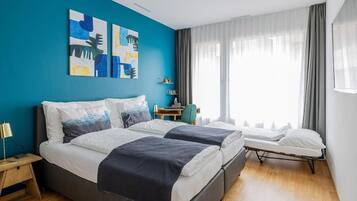 Una habitación de hotel moderna con dos camas, un escritorio y una ventana con cortinas.