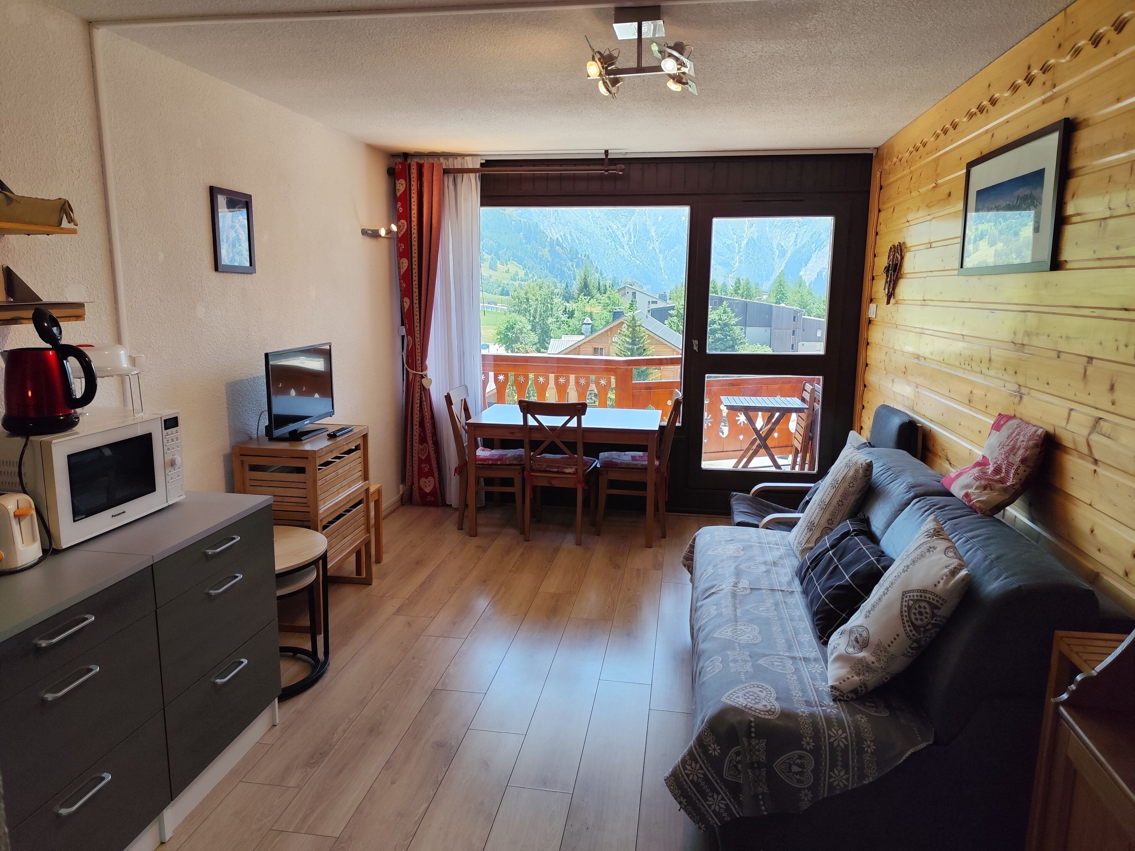 Un salon confortable avec un canapé, une télévision, un four à micro-ondes et des meubles en bois.