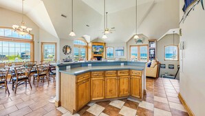 A spacious kitchen with a large island, wooden cabinets, and a view of the ocean. - Premier Oceanfront Dog Friendly w/ Pool, Elevator, Hot Tub, Game and Media Rooms (Hatteras)