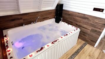 A modern bathroom with a freestanding bathtub, wooden flooring, and a heart-shaped decoration on the floor.