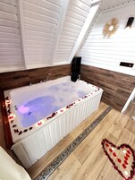 Un baño moderno con una bañera independiente, suelo de madera y una decoración con forma de corazón en el piso.