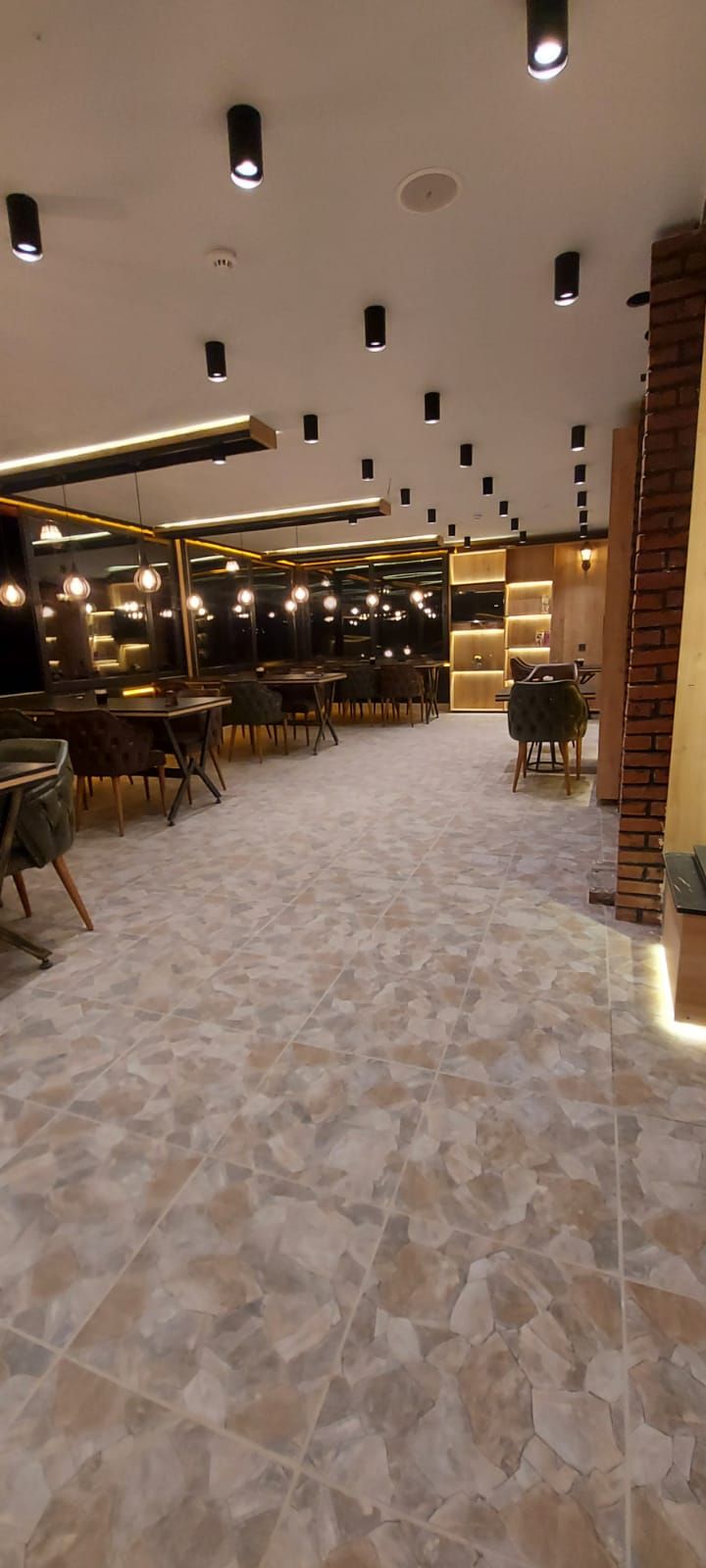 A spacious restaurant with a high ceiling, multiple tables, and a patterned floor.