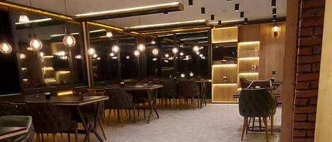 A spacious restaurant with a high ceiling, multiple tables, and a patterned floor.