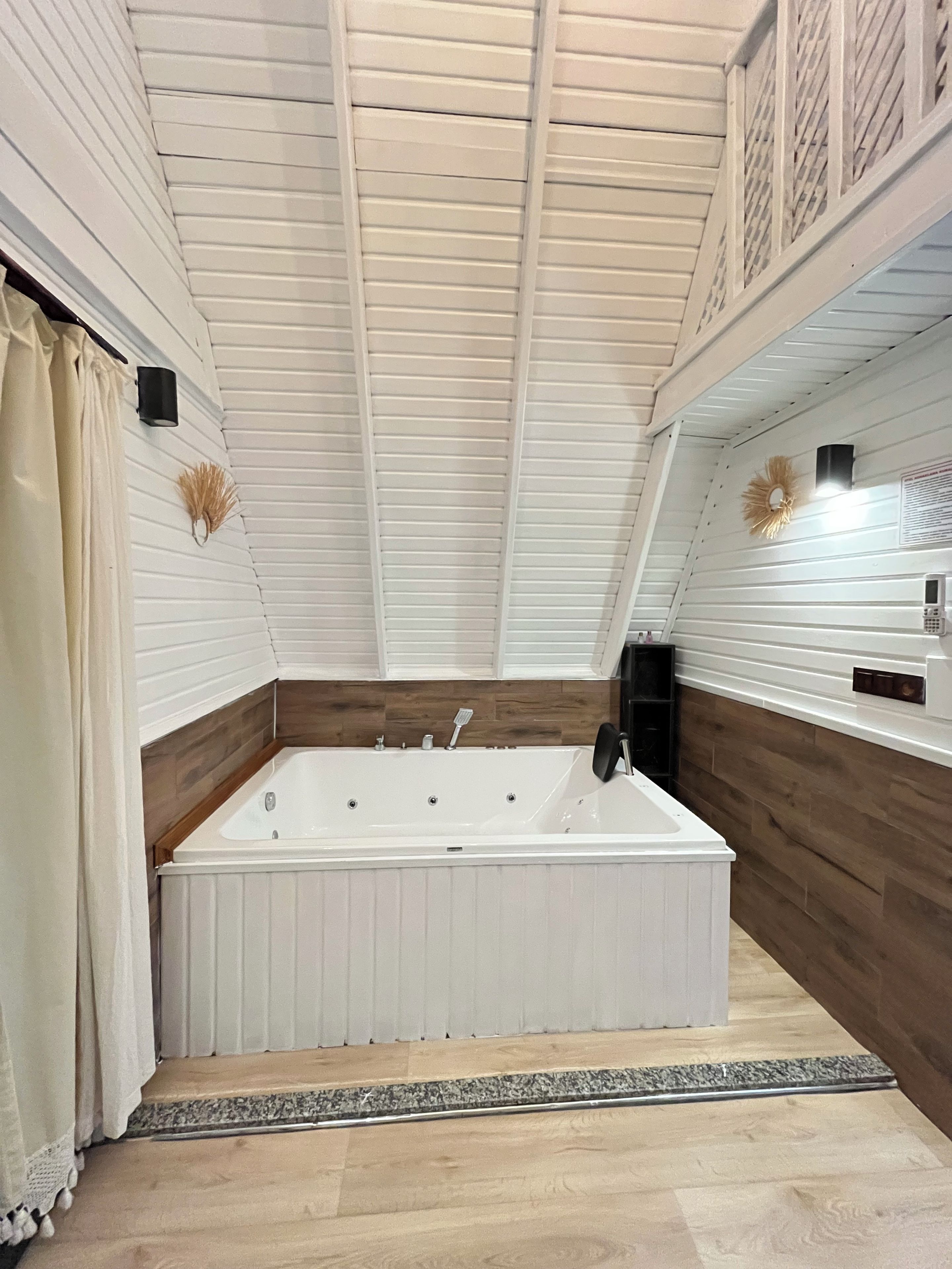 A modern bathroom with a freestanding bathtub, wooden paneling, and a ceiling with exposed beams.