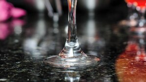 Ett cocktailglas med en apelsinskiva som garnering och en kvist rosmarin.